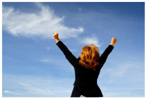 Image of a triumphant business-woman with her arms in the air