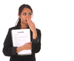 Image of a woman holding a resume, looking shocked at what she's heard