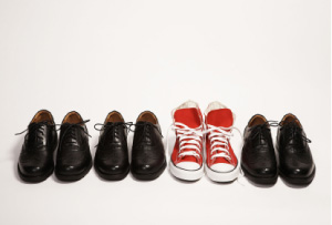 Picture of lined up black work shoes - with a pair of red converse sneakers standing out, in the middle